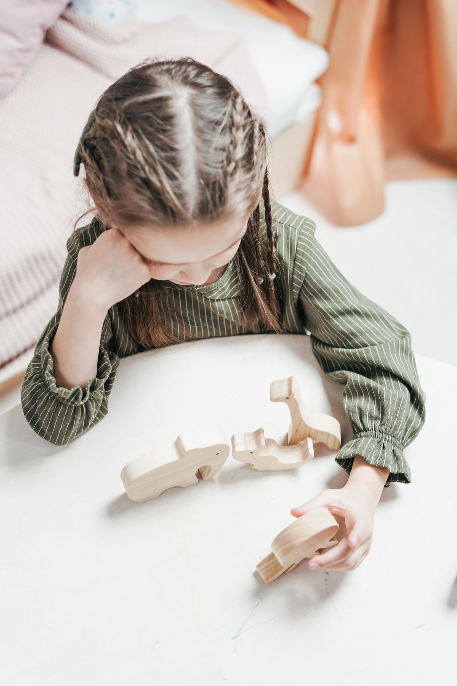 A girl resting her head on a table beside unfinished building blocks