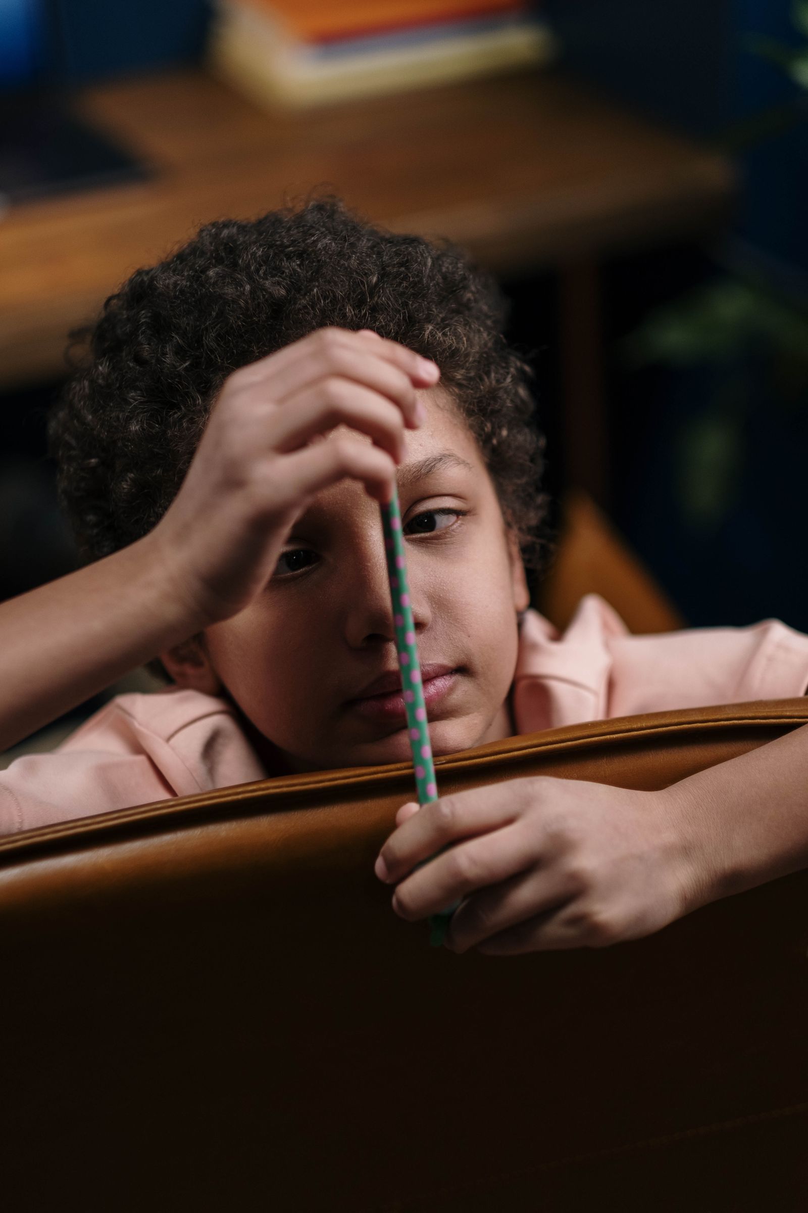 A boy resting his head on a desk holding a pencil